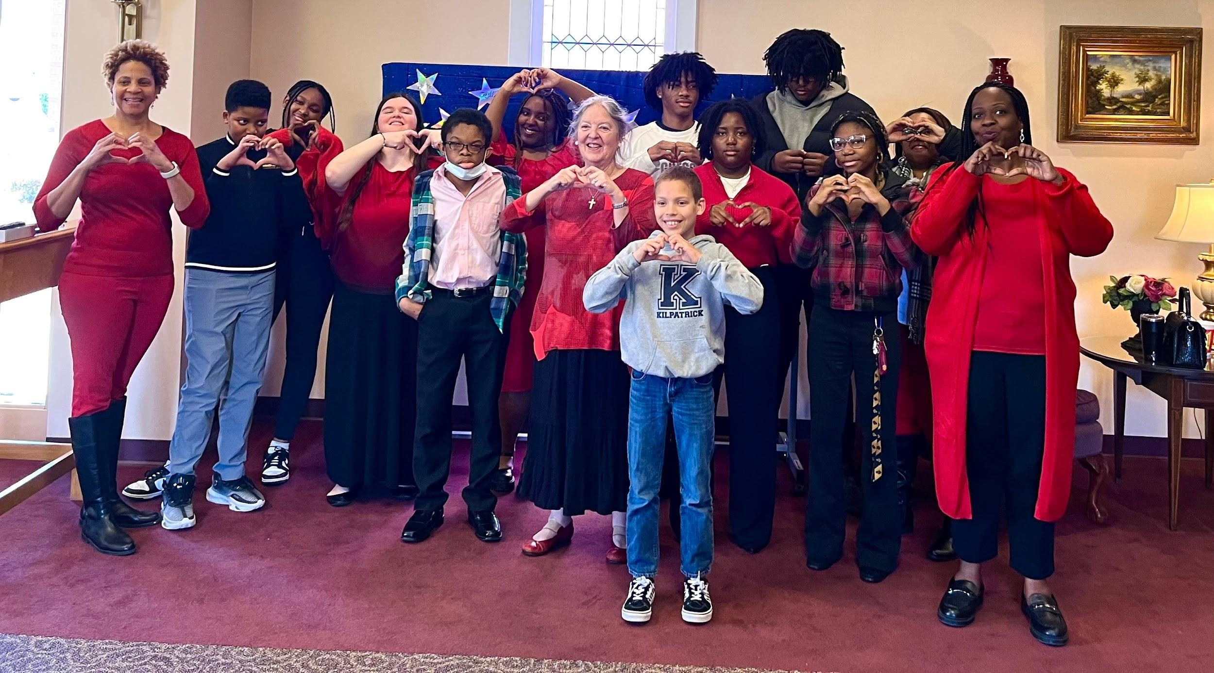 Group of people posing together indoors, some making hand signs.