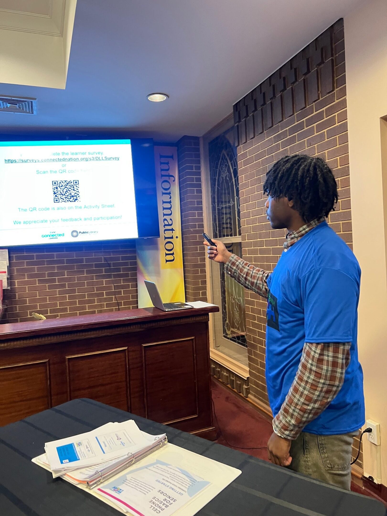 Person scanning QR code from a presentation screen with a mobile phone.