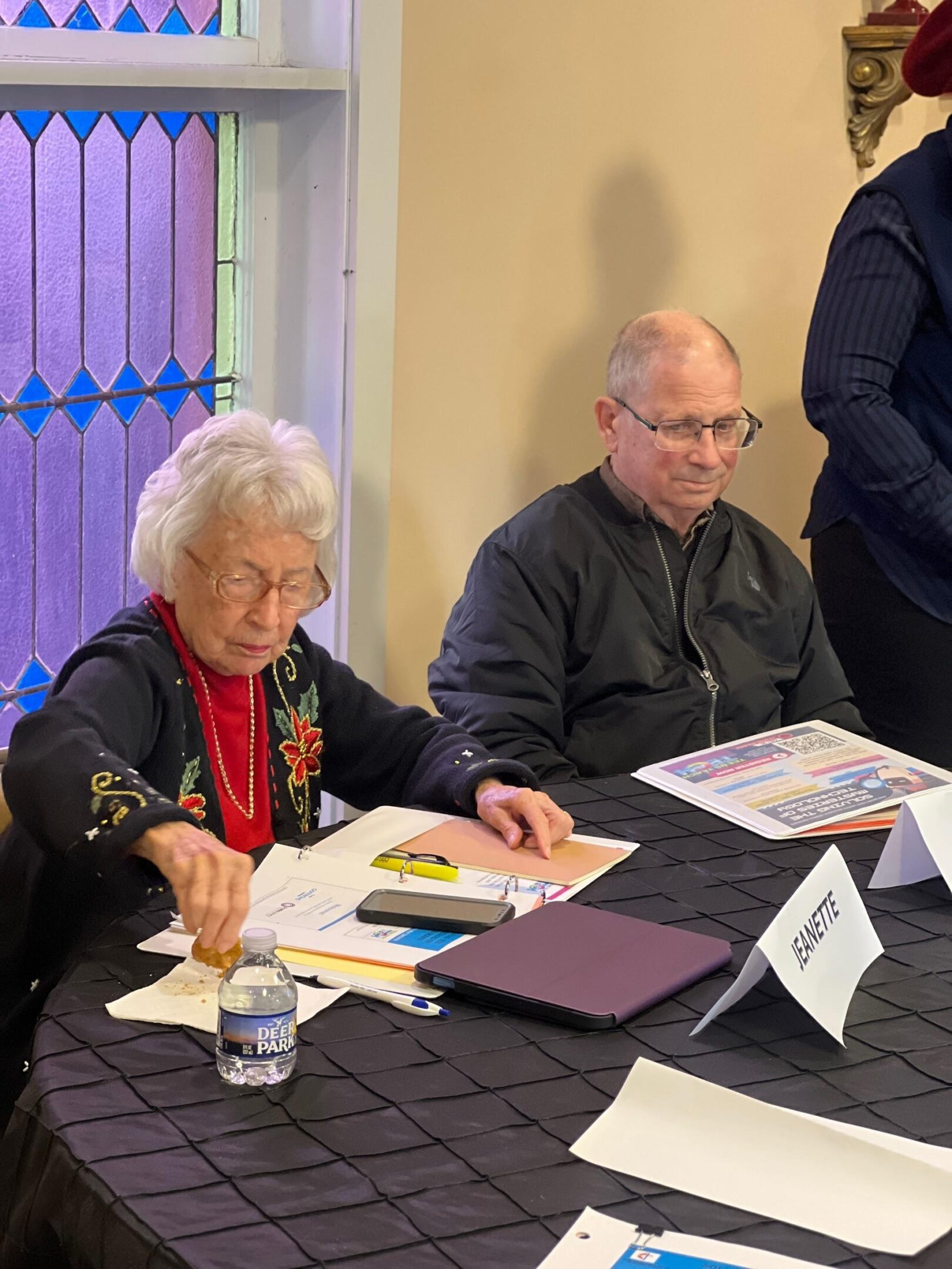 Two people sitting at a table, engaged in paperwork.