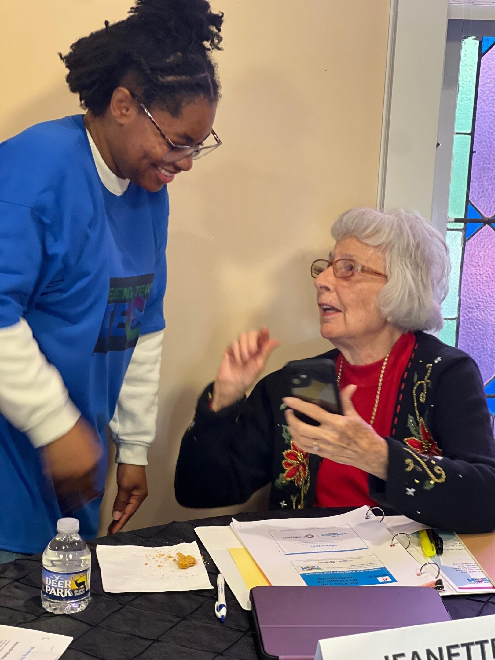 Older woman and man engaging in a friendly conversation indoors.