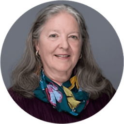 Portrait of a smiling elderly woman with long gray hair and a colorful scarf.