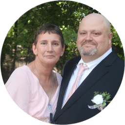 A couple dressed formally posing outdoors in a circular frame.