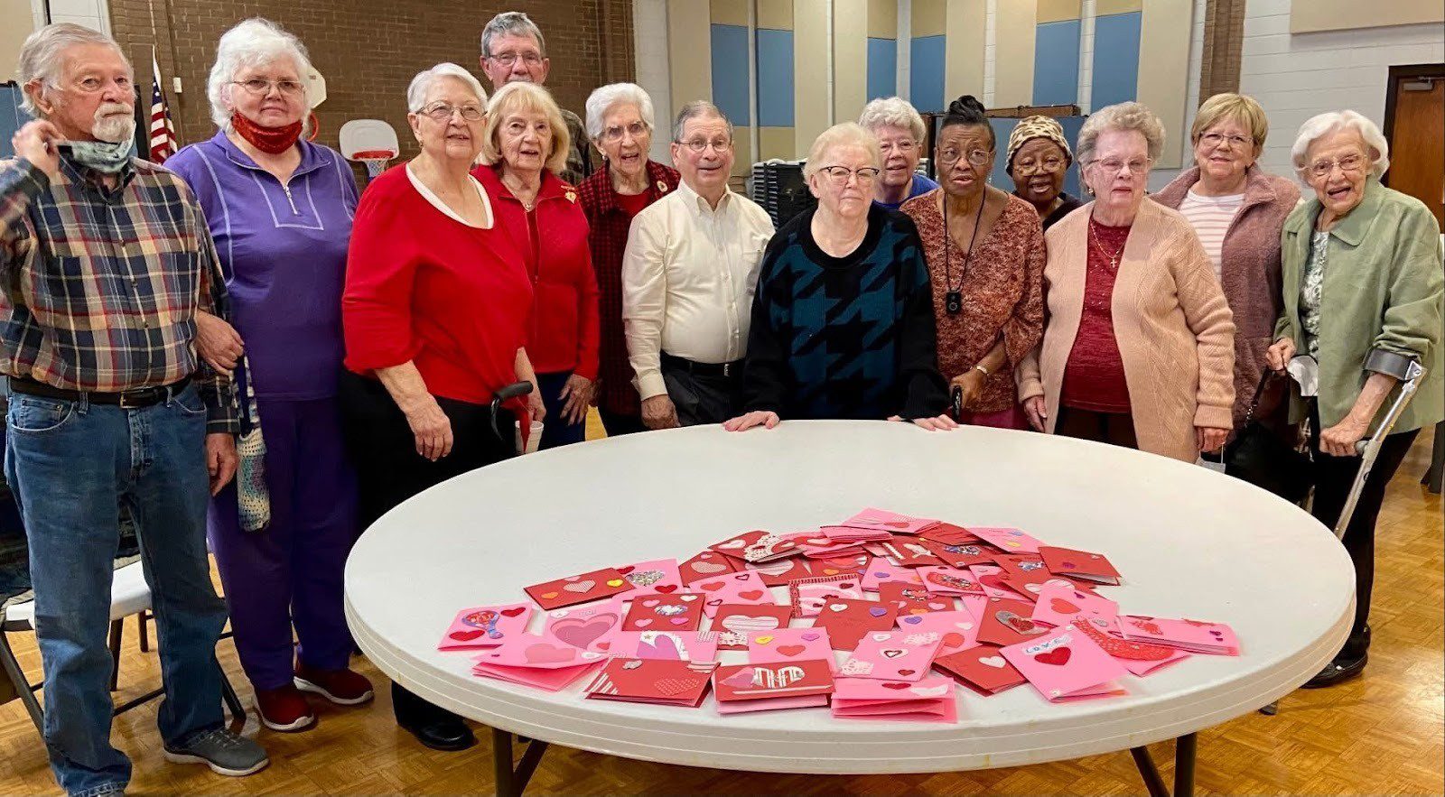 Group of elderly women gathered around a table with pink cards.
