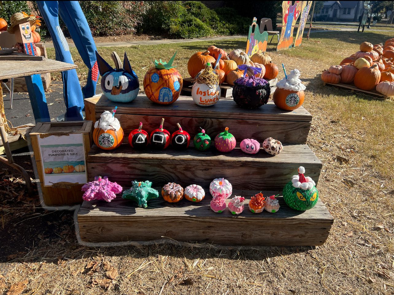 Decoratively painted pumpkins displayed outdoors on wooden steps.