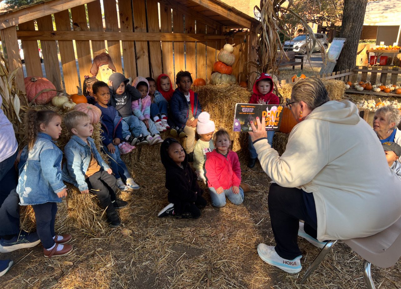 A group of children attentively listening to a storyteller in a barn.