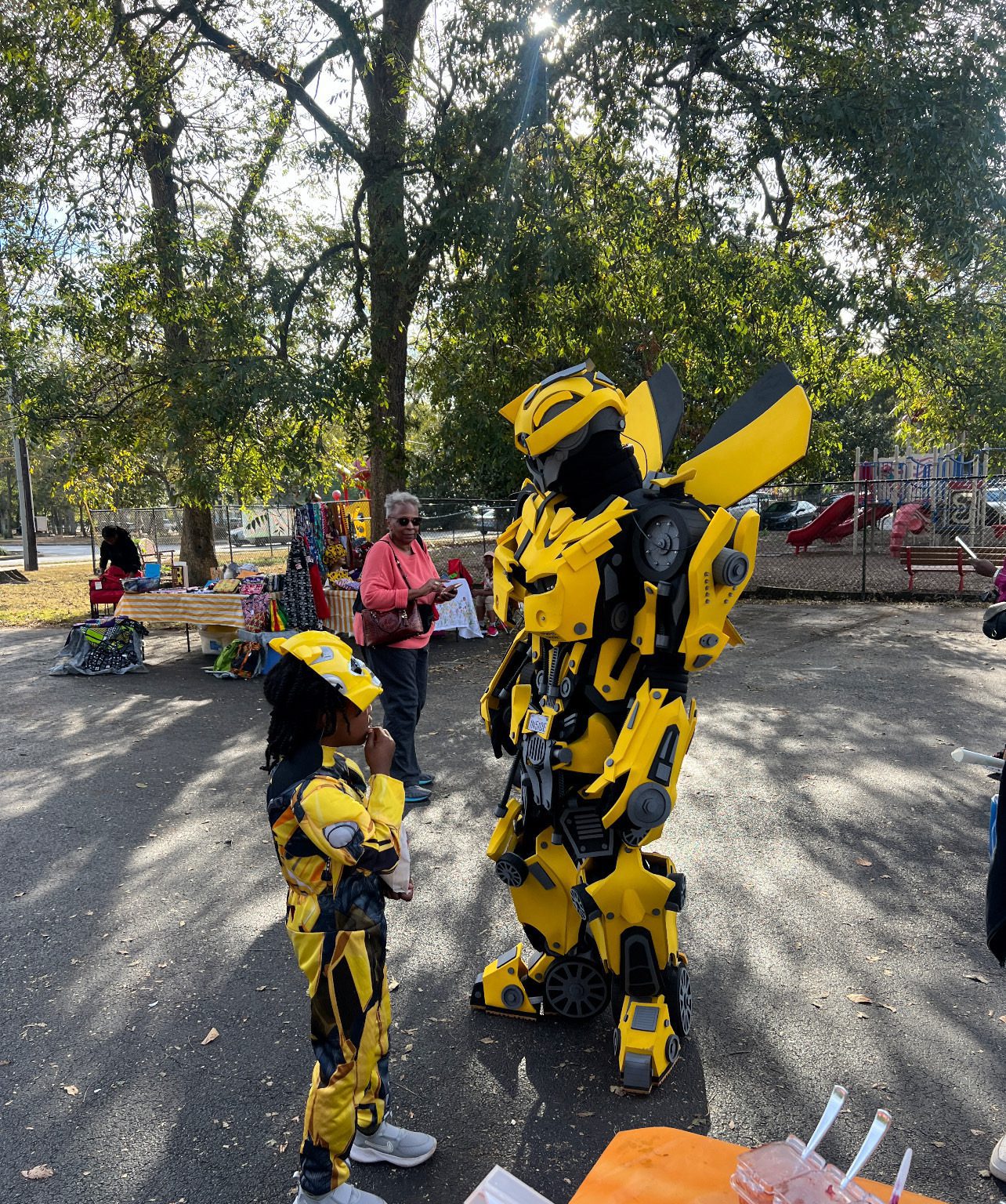 Two people dressed in yellow and black Bumblebee costumes outdoors.