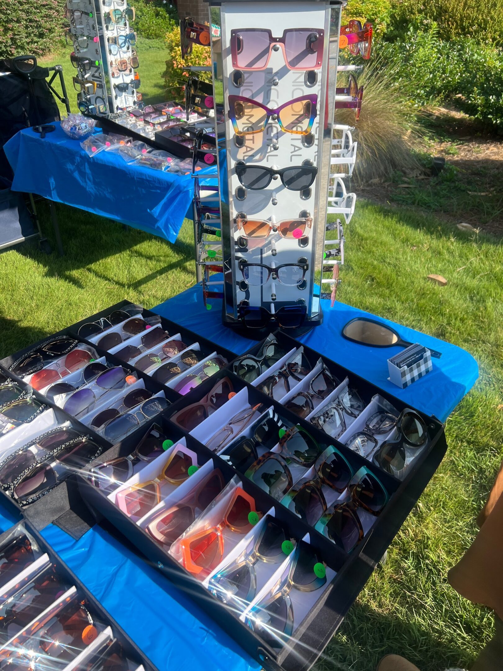 Vendor table displaying an assortment of colorful sunglasses outdoors.