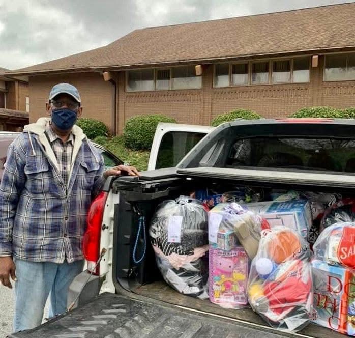 Man stands next to a pickup truck loaded with bags of supplies.