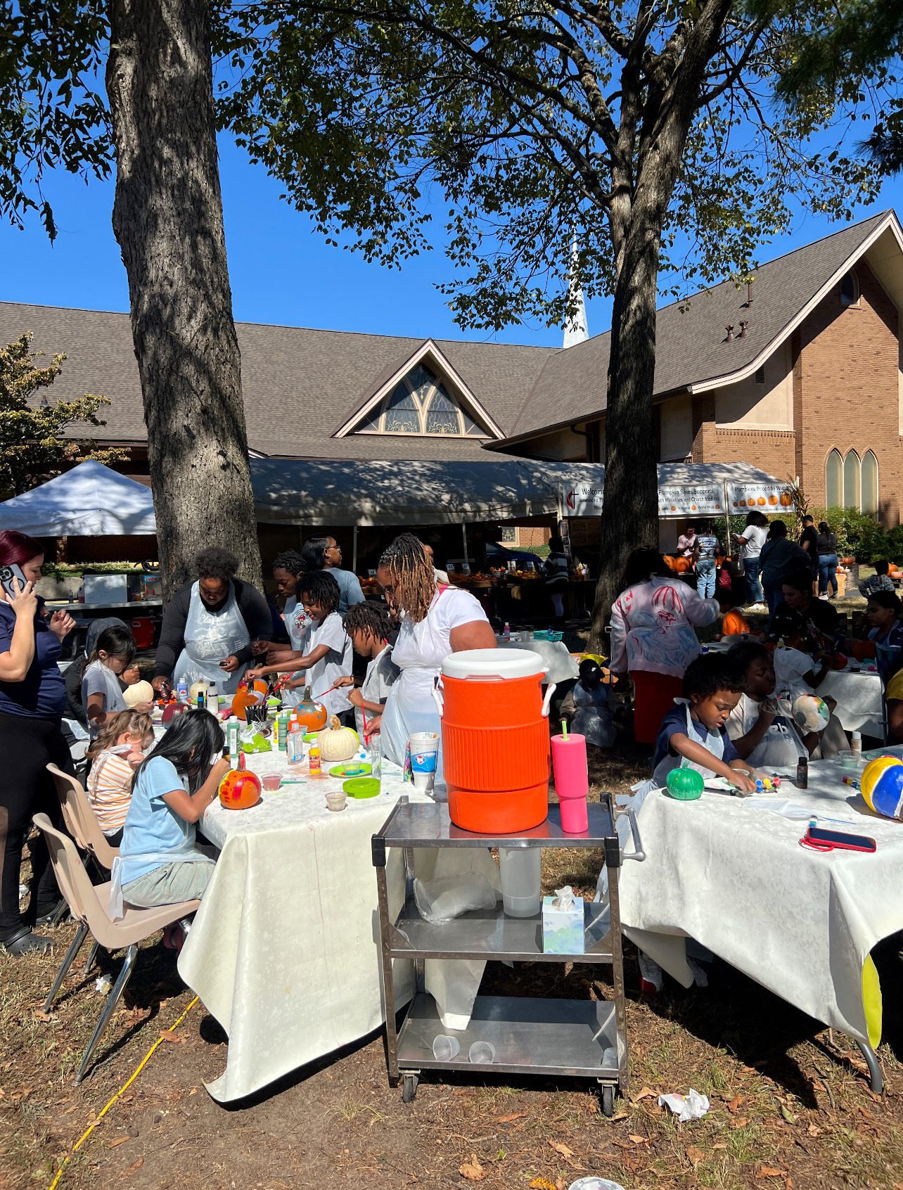 Outdoor gathering with people enjoying food under trees.